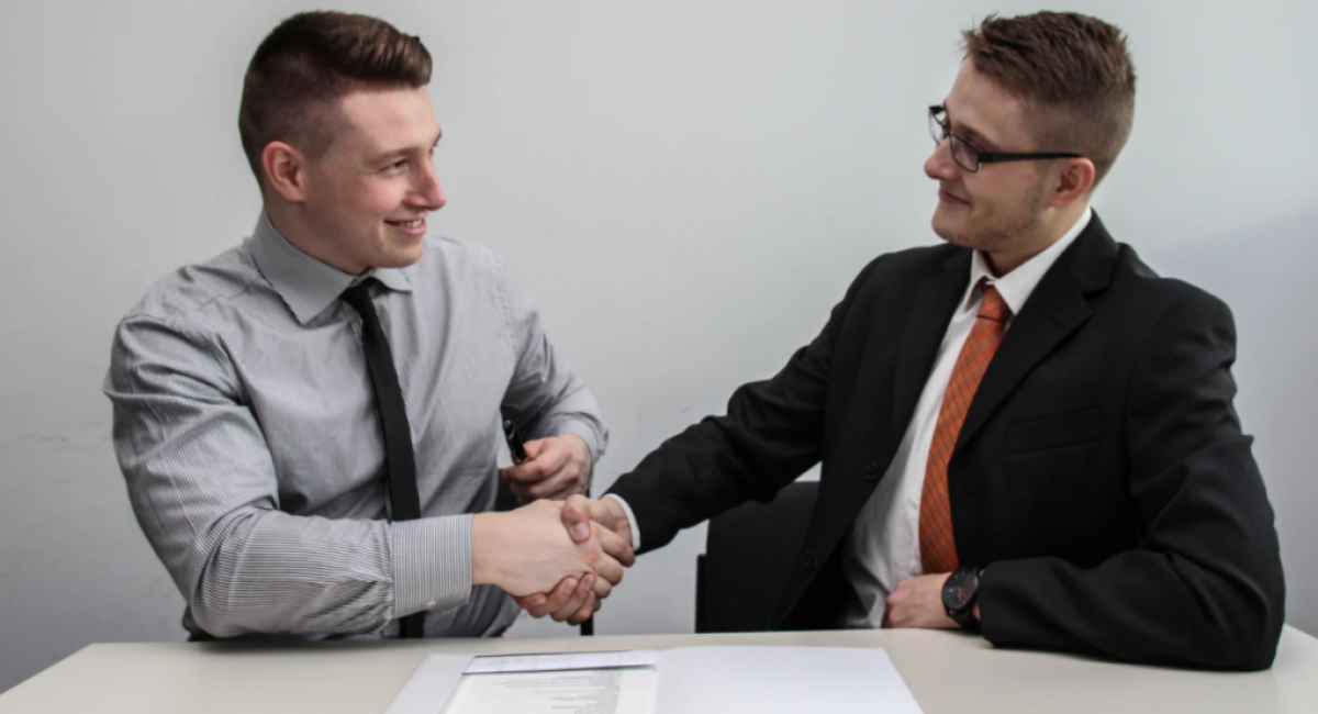 Glad to meet you! Two businessmen at a table shaking hands