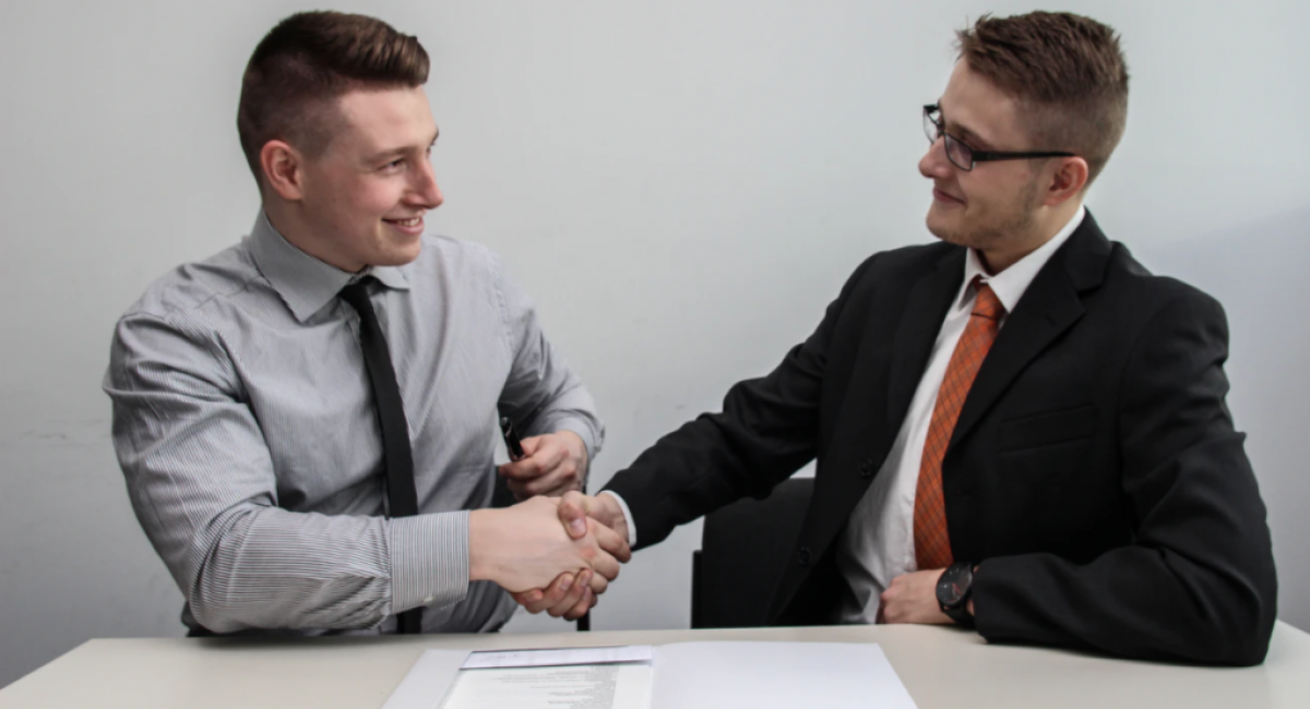 Two businessmen at a table shaking hands