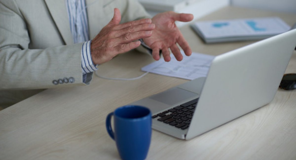 Man's hands clapping in front of a laptop