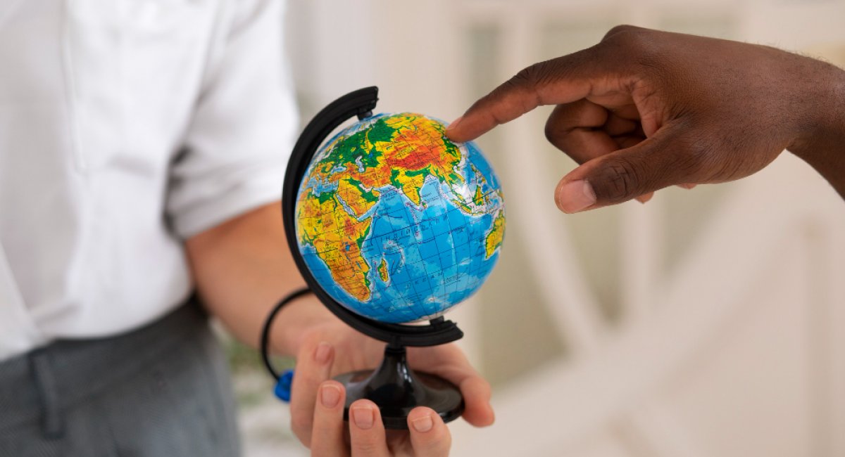 A hand pointing at a globe