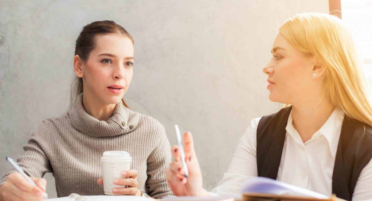 Two young women talking in an office