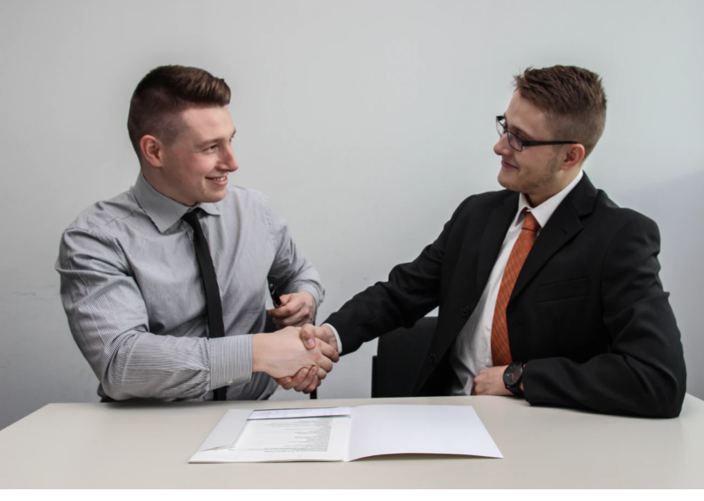 Two businessmen at a table shaking hands