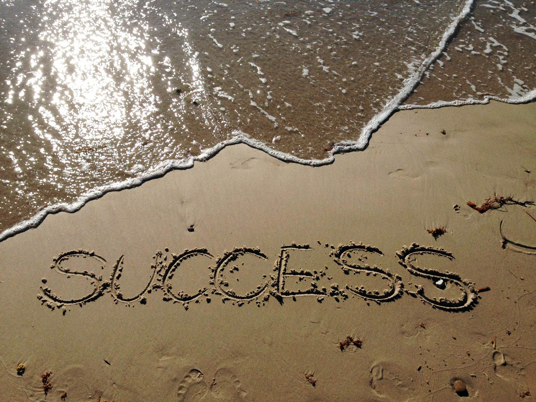 The word "success" written in the sand on a beach