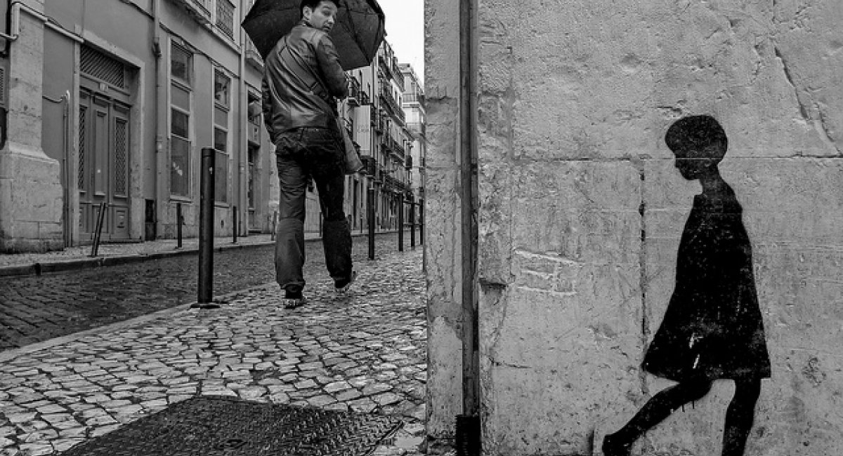 man walking cobblestone street looking back silhouette girl stencil wall
