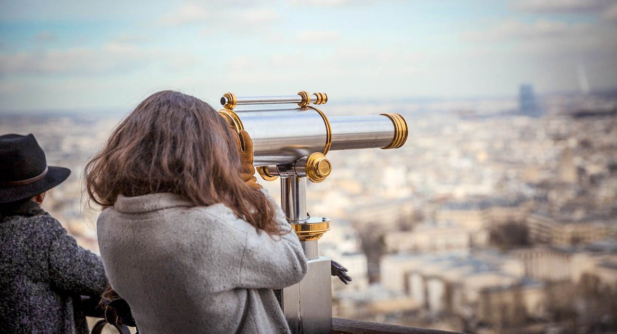 Young woman looking through telescope on an observatory deck