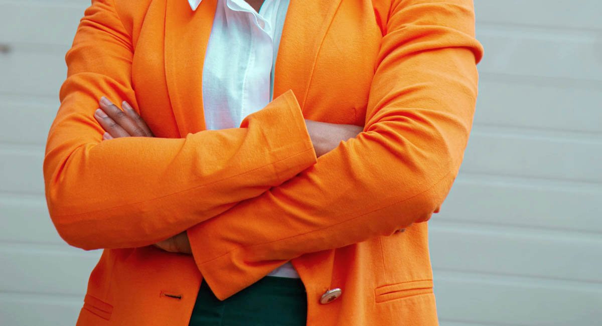 Woman in orange blazer with arms crossed