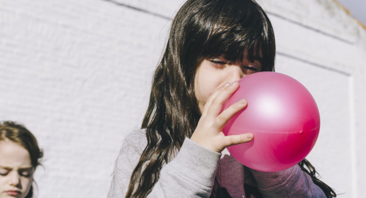 girl blowing up balloon