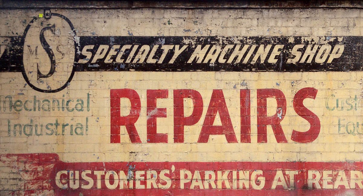 Some writing on a wall about a repair shop