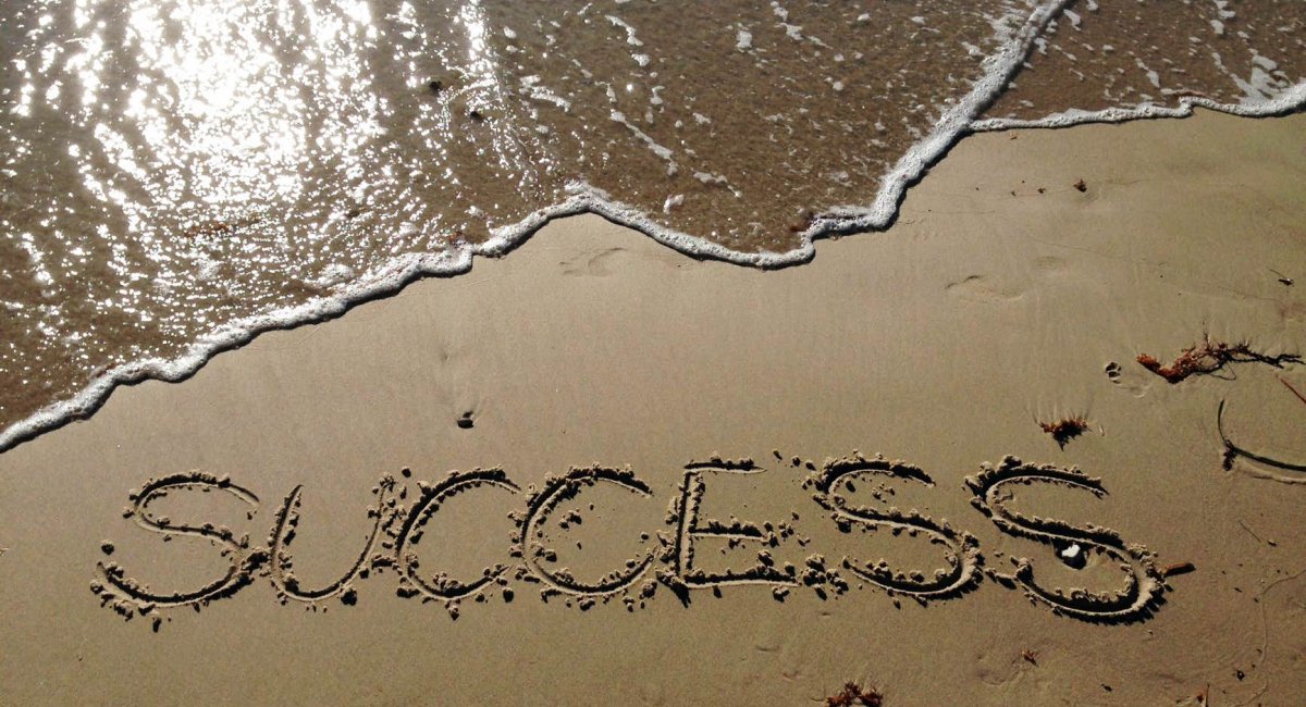 The word "success" written in the sand on a beach
